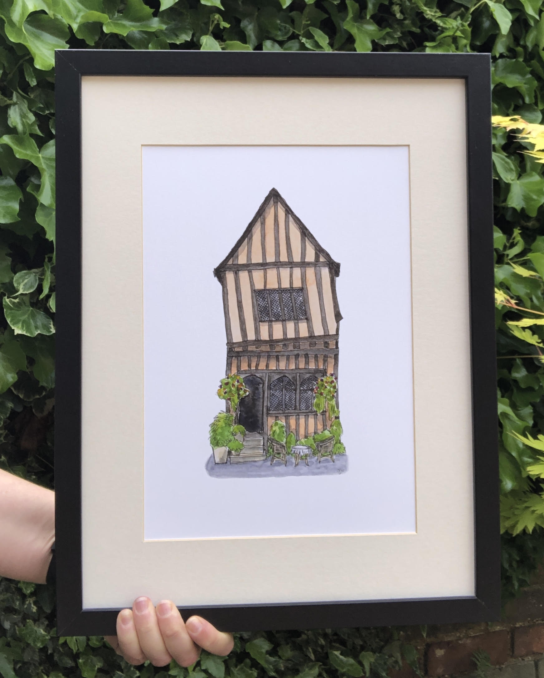 A4 print of Crooked House, Lavenham, presented in a black frame with ivory mount